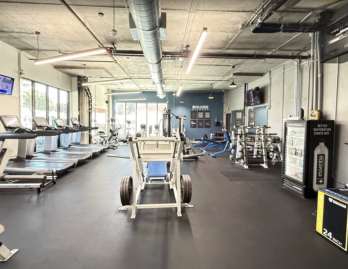 Main floor at Bolder Fitness with treadmills, plate-loaded machines, and dumbbell racks